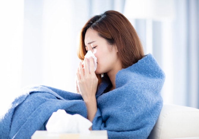 毛布にくるまり鼻をかむ女性