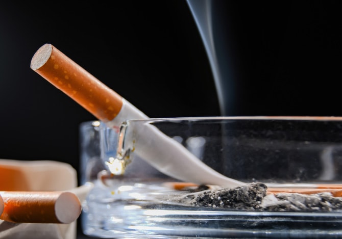 灰皿に置かれた火が付いたタバコ
